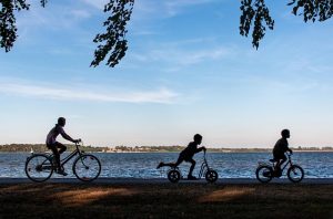 personen auf roller, fahrrad am Wasser